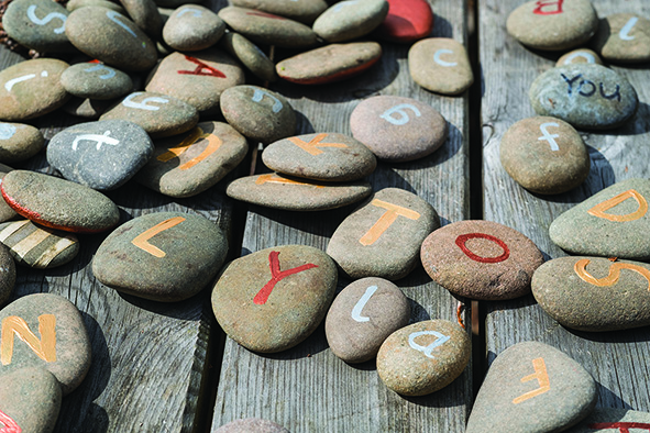 Pebbles painted with letters sitting on decking