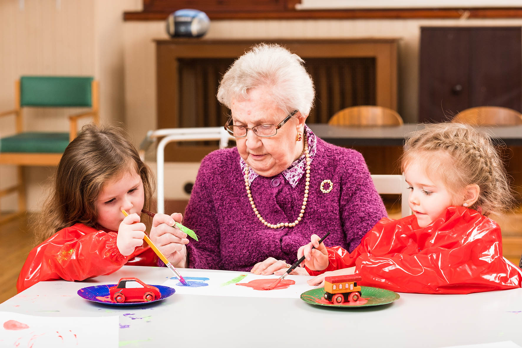 Older woman with two young girls painting