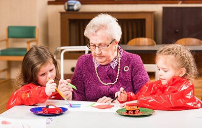 Older woman with two young girls painting