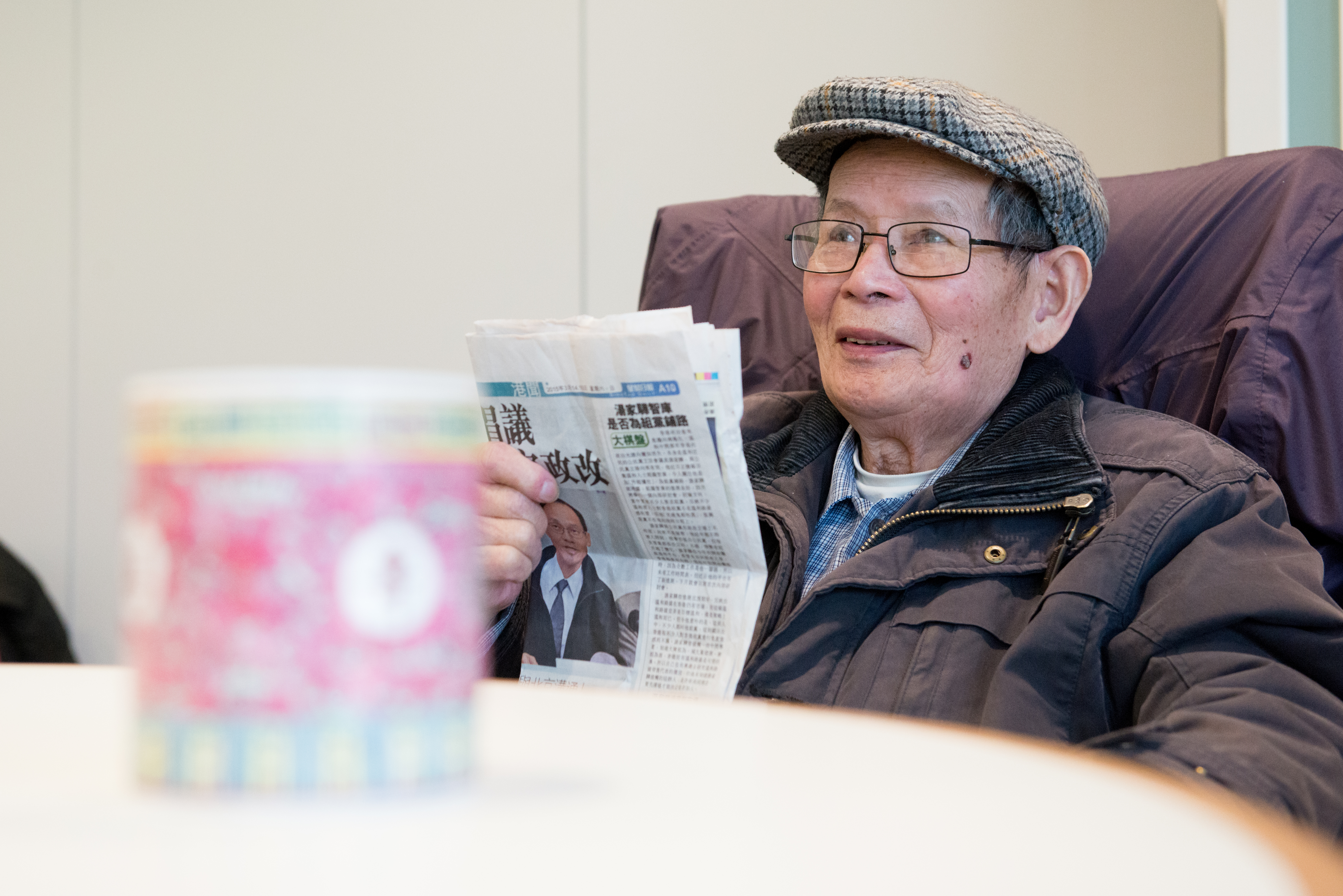 Older man wearing a bonnet reading a newsletter