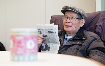 Older man wearing a bonnet reading a newsletter