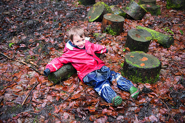 Boy lying on wet leaves