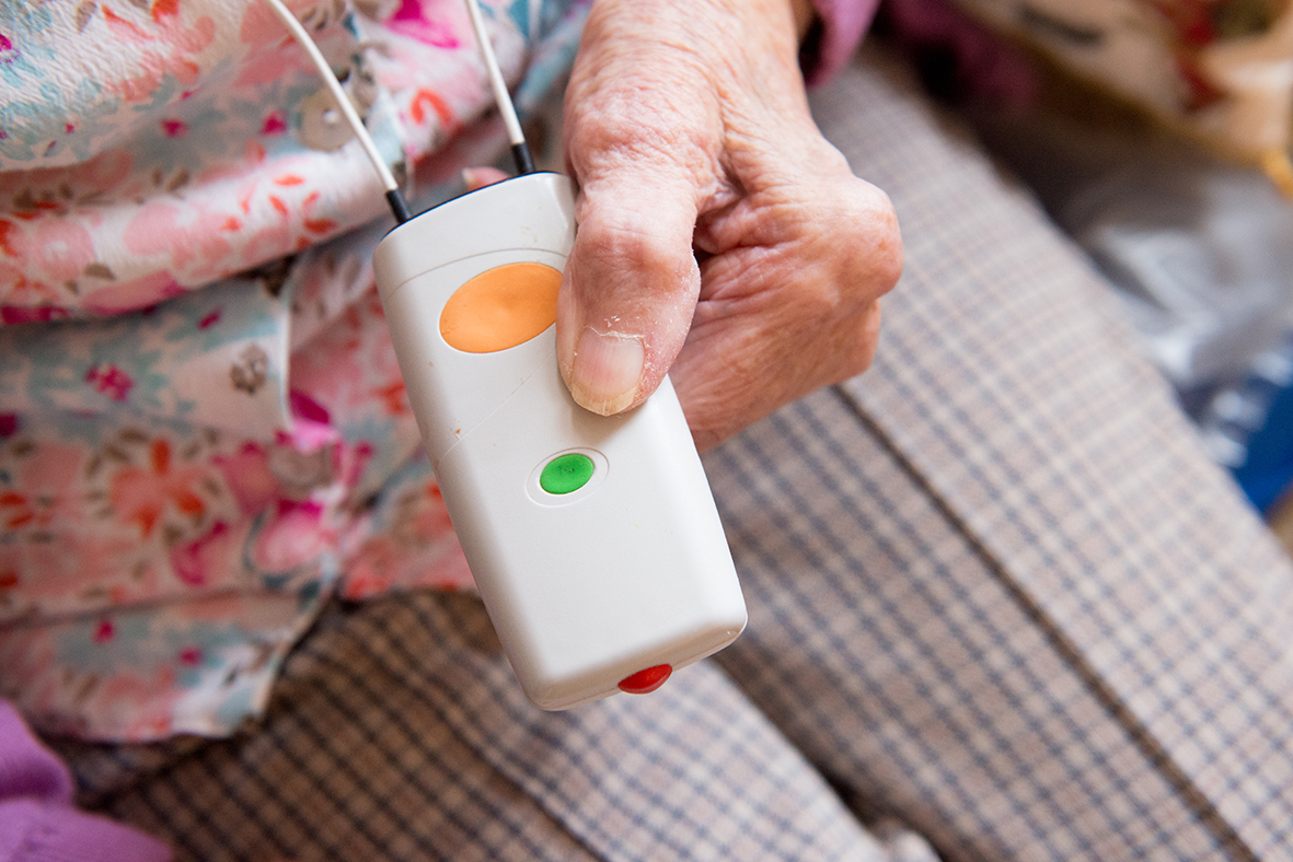 Person pressing a button on a care alarm device