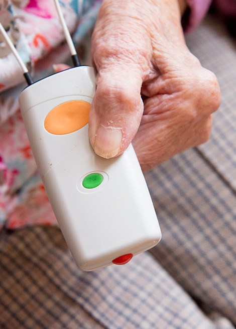 Person pressing a button on a care alarm device