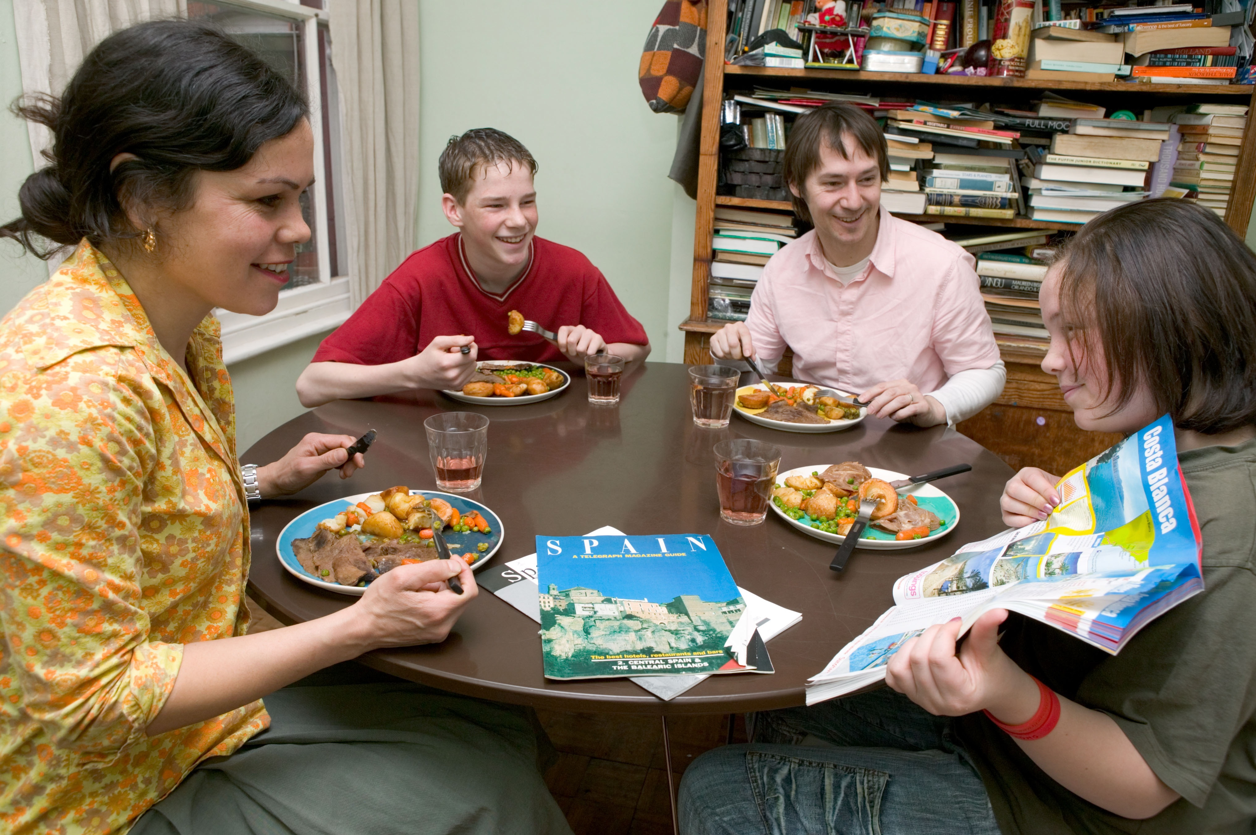 Children having a meal at a table looking at a travel brochure