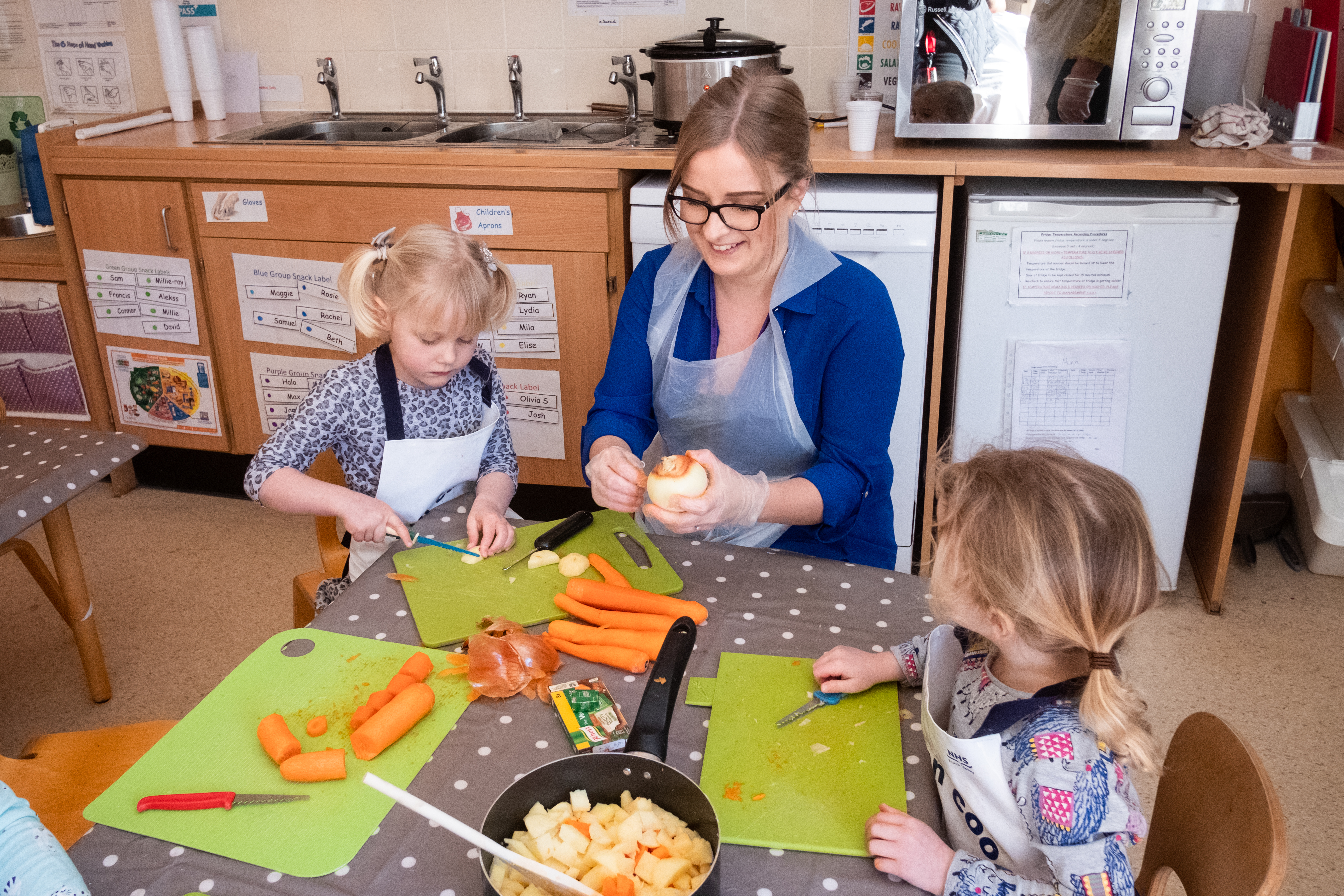 Staff and children cutting up vegetables in a nursery setting