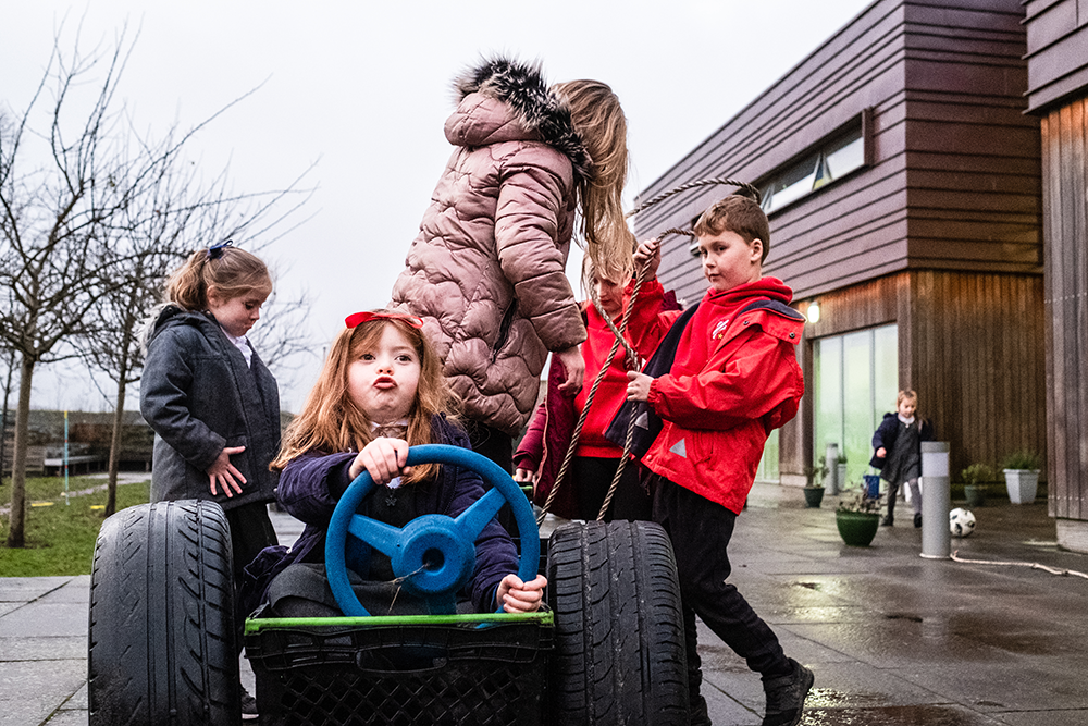 Group of children playing outside on a toy car