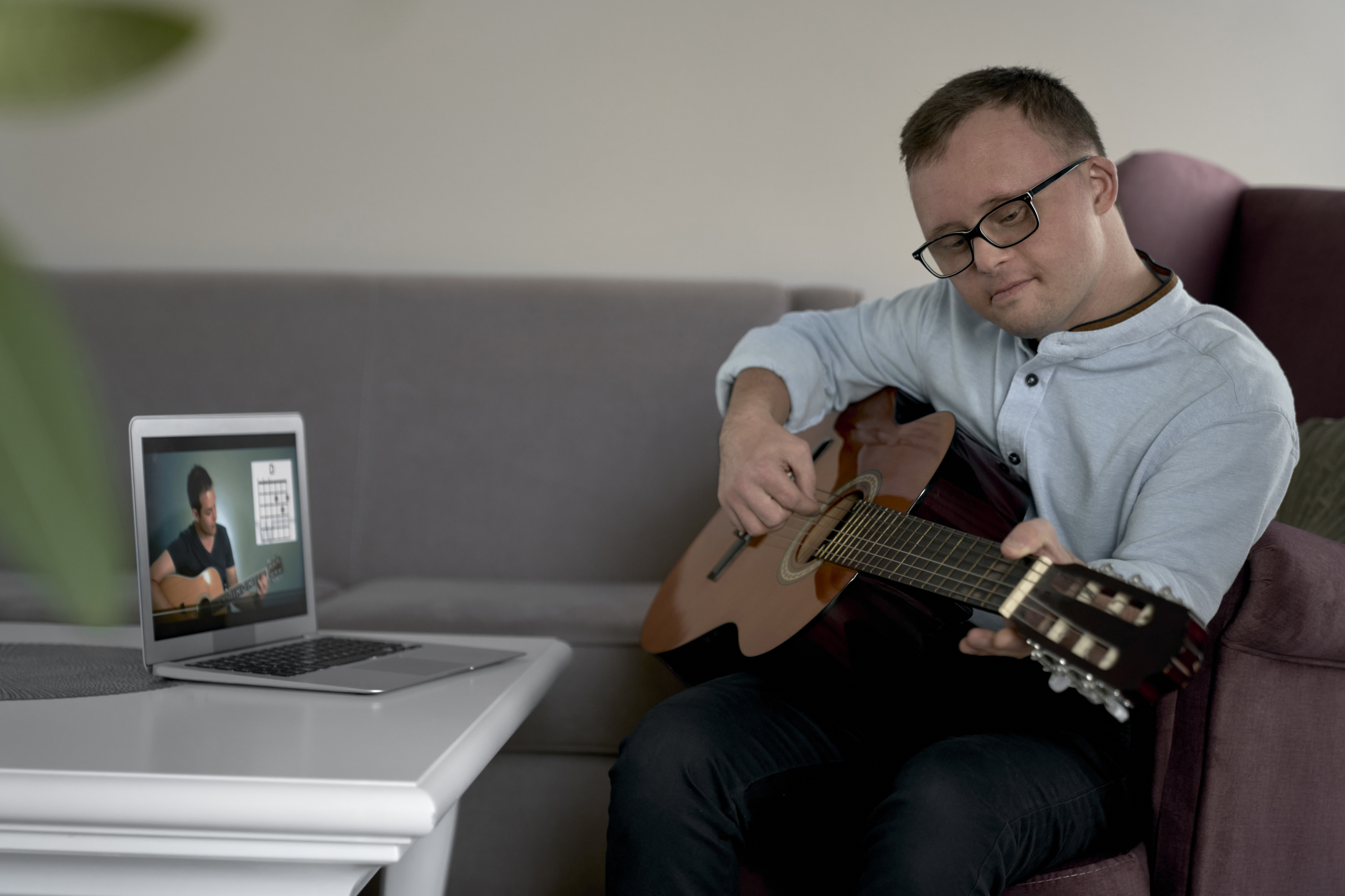 Adult man with Downs syndrome learning to play the guitar