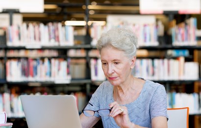 Women sitting in a library looking at a laptop.
